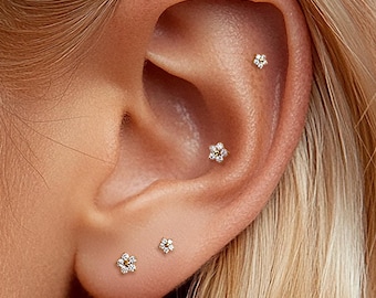 May include: A set of five small silver-toned stud earrings shaped like tiny flowers, each featuring clear sparkling stones. The earrings are placed in various positions along the earlobe, helix, and conch, creating a coordinated arrangement.
