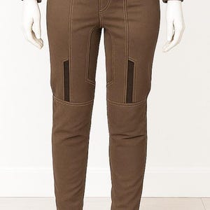 May include: Brown trousers with contrasting stitching and dark brown panels on the knees. The trousers are displayed on a mannequin. The trousers have a tailored fit and a classic design, suitable for various occasions.