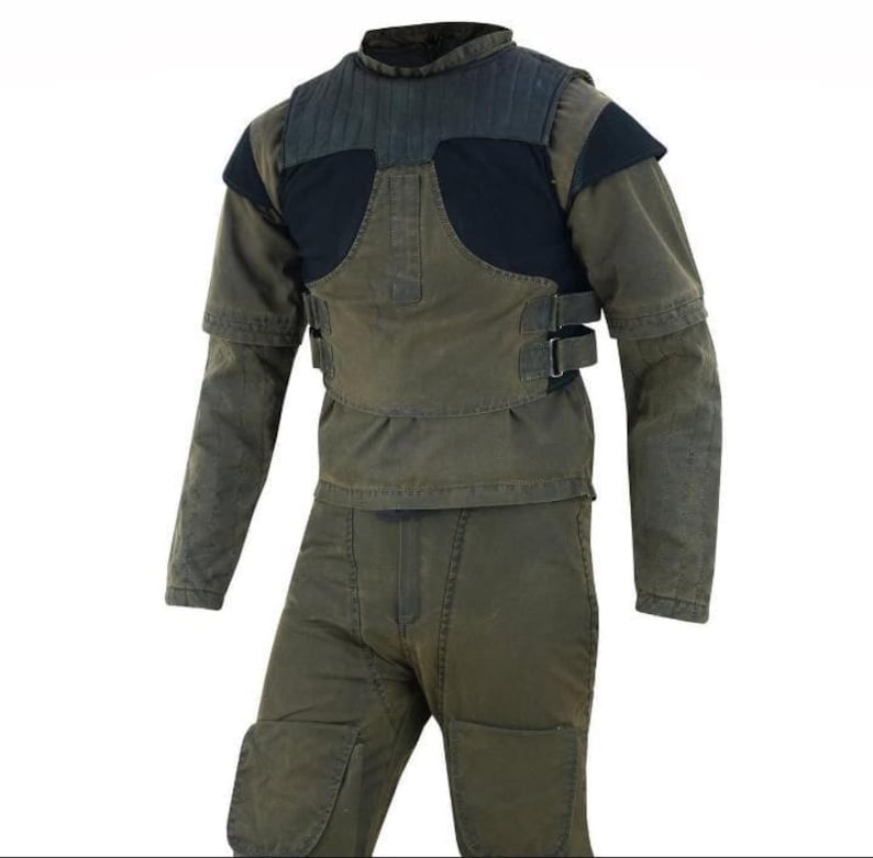 K&ouml;nnte beinhalten: Ein zweiteiliges olivgr&uuml;nes Kleidungsst&uuml;ck-Set. Das Oberteil hat einen hohen Kragen, schwarze Schulter- und Brustpartien sowie zwei verstellbare Riemen. Das lang&auml;rmlige Oberteil und die Hose sind aus strapazierf&auml;higem Stoff gefertigt.