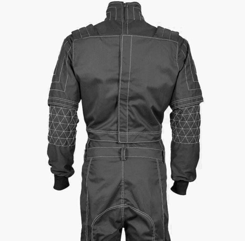 May include: A black racing suit with white stitching. The suit features a high collar, long sleeves, and a belt at the waist. The shoulders and upper arms have geometric patterns. The suit has black cuffs at the wrists and ankles.