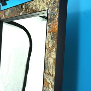 En spegel i svart aluminium- och granitram – modern, lyxig och handgjord. En spegel för badrummet eller vardagsrummet.