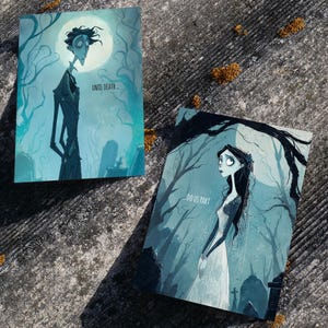 以下が含まれることがあります： 青とグレーの色合いのイラストが描かれた2つのアートプリント。1つのプリントには「UNTIL DEATH...」というテキストが入った背の高い人物が描かれています。もう1つのプリントには「DO US PART」というテキストが入った女性が描かれています。どちらのプリントもゴシックテーマです。