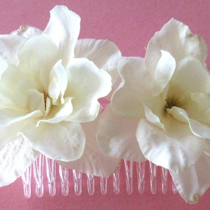 May include: A white flower hair comb with two large white flowers. The comb has a clear plastic base with teeth.