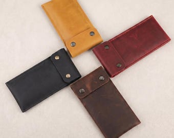 May include: Four leather eyeglass cases in various colors: black, brown, yellow, and burgundy. Each case has a flap closure secured by two metal snaps. The cases are rectangular and appear to be made of genuine leather.