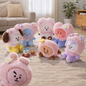 May include: A collection of plush character dolls in various colors, including yellow, blue, and purple. Each doll has a pink hooded outfit with floral or animal-themed accents. Some dolls have small food props.