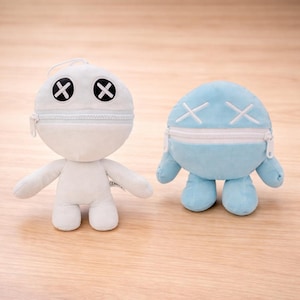 Puede incluir: Dos muñecos de peluche, uno blanco y otro azul claro, cada uno con una cabeza con cremallera y ojos cosidos en forma de cruz. Los muñecos tienen brazos y pies pequeños y un diseño minimalista.