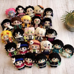 May include: A selection of plush dolls depicting characters with distinctive hairstyles and clothing. The dolls have a variety of hair colours, including black, pink, and yellow. Some dolls are wearing patterned outfits and accessories.