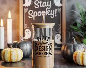 May include: A clear glass tumbler with a bamboo lid and straw, filled with a light brown liquid. The text "PLACE YOUR DESIGN HERE" is printed on the front. The background includes a chalkboard with "Stay Spooky!" and ghost illustrations, pumpkins, and lit candles.