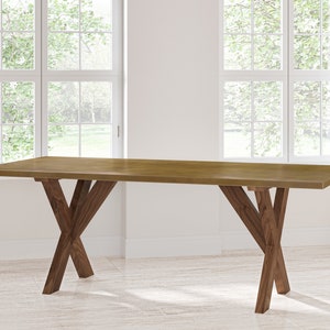 May include: A long, rectangular wooden table with a natural brown finish. The table has a unique X-shaped base made of two pieces of wood that cross each other.