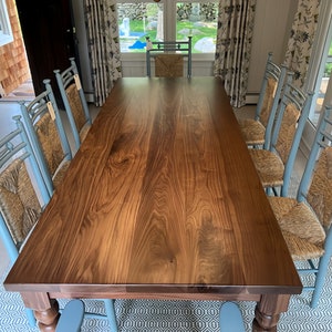 May include: A large, dark wood dining table with a natural wood finish. The table is surrounded by eight blue chairs with woven cane seats.