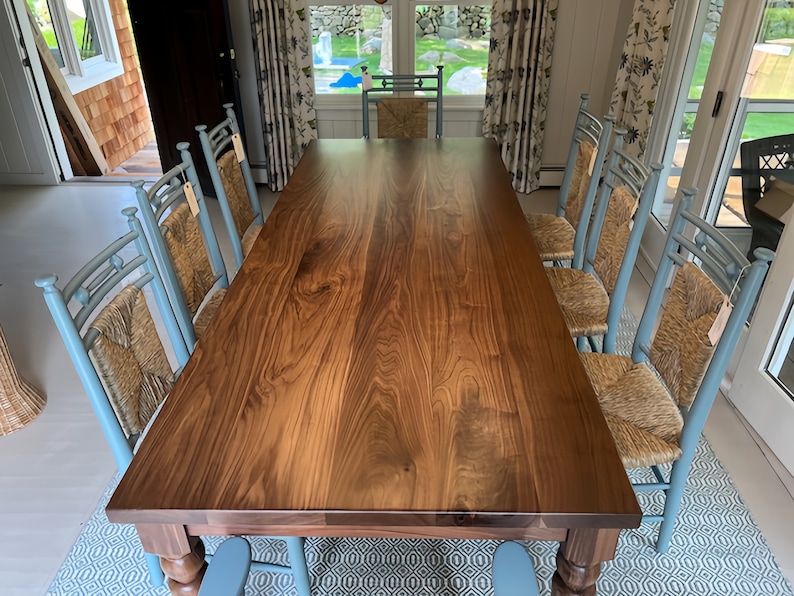 May include: A large, dark wood dining table with a natural wood finish. The table is surrounded by eight blue chairs with woven cane seats.