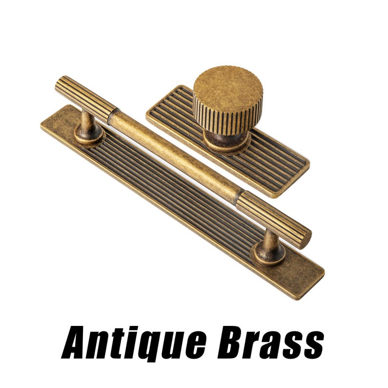 Puede incluir: Juego de herrajes para armarios de lat&oacute;n antiguo. El juego incluye un tirador largo con dos postes, un pomo con base rectangular y un tirador m&aacute;s peque&ntilde;o. El herraje tiene un dise&ntilde;o acanalado y un acabado vintage. El texto "Antique Brass" est&aacute; en la parte inferior.
