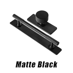 Puede incluir: Juego de herrajes para armarios negro mate, que incluye un tirador largo, un pomo y un tirador m&aacute;s peque&ntilde;o. Los herrajes tienen un dise&ntilde;o acanalado y se muestran sobre un fondo blanco. El texto "Matte Black" se muestra debajo.