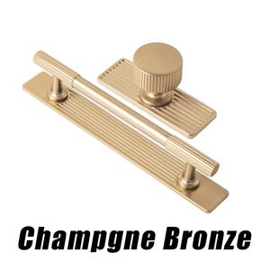 Puede incluir: Juego de herrajes para armarios Champagne Bronze. El juego incluye un tirador largo, un pomo y un tirador m&aacute;s peque&ntilde;o, todos en acabado bronce champ&aacute;n. El herraje tiene un dise&ntilde;o acanalado y est&aacute; sobre fondo blanco.