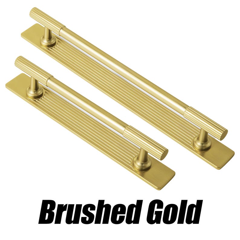 Puede incluir: Dos tiradores de armario dorados cepillados con un dise&ntilde;o acanalado. Cada tirador tiene una base rectangular y un asa cil&iacute;ndrica. El texto "Brushed Gold" se muestra en negrita negra.