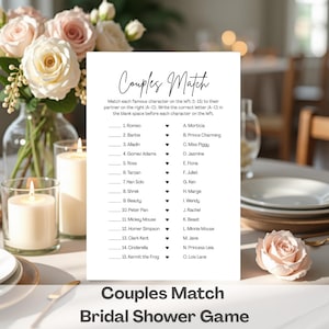 May include: A white Couples Match bridal shower game card with a list of characters to match. The card is surrounded by flowers, candles, and a rose. The game includes characters like Romeo, Barbie, and Aladdin.