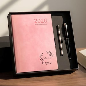 May include: A pink 2026 schedule notebook with the name "Maisie" and a leaf design, in a black gift box. Includes a silver pen and a black pen.