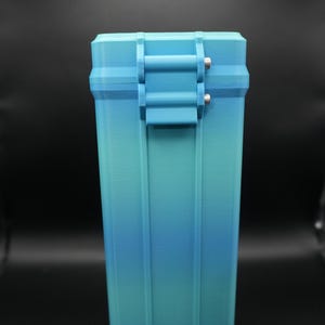 May include: A rectangular, blue and teal case with a hinged lid and a clasp closure. The case has vertical lines on the sides and a gradient color scheme, transitioning from teal to blue. The clasp is a lighter shade of blue.