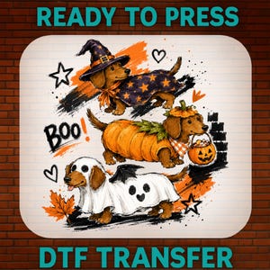 Peut inclure: Un transfert DTF prêt à presser illustrant trois teckels en costumes d'Halloween. L'un porte un chapeau de sorcier et une cape étoilés, un autre est déguisé en citrouille avec un seau jack-o'-lantern, et le troisième porte un drap de fantôme. Texte BOO.