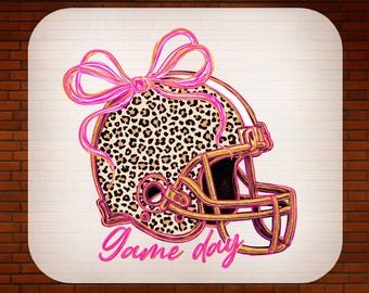 May include: A pink and gold football helmet design with a leopard print pattern, a pink bow, and the words "Game day." The text "READY TO PRESS" and "DTF TRANSFER" are also included. This design is suitable for apparel.