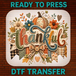 Peut inclure: Une feuille de transfert DTF avec le mot Thankful en écriture cursive à motifs écossais et floraux. Le design comprend une citrouille centrale, des fleurs d'automne, des feuilles, des cœurs et un nœud avec un bouton sur fond blanc.