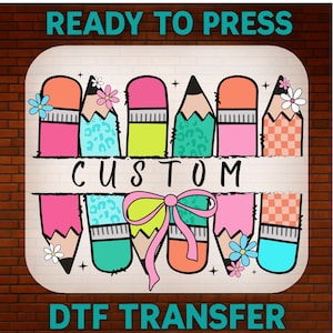May include: A vibrant DTF transfer design with pencils, erasers, and floral details. The word "CUSTOM" is in the middle, with "READY TO PRESS" and "DTF TRANSFER" above and below. The design is set against a brick background.