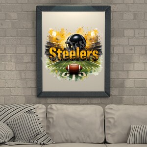 Pu&ograve; includere: Opera d'arte incorniciata raffigurante un campo da football con un pallone e un casco nero. La parola "Steelers" &egrave; in giallo e nero. Lo sfondo mostra uno stadio con luci brillanti. L'opera &egrave; incorniciata in una cornice grigio scuro.