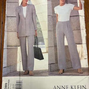 Op de afbeelding: Een vintage Anne Klein naaipatroon met een vrouw in een lichtgrijs pak en een andere in een grijze broek en een witte top. Het patroonnummer is 2389, maten 6-8-10. Het Vogue American Designer-logo is zichtbaar.