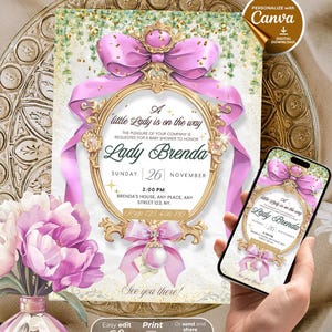 Puede incluir: Una invitación para un baby shower con un lazo rosa y un marco dorado. La invitación dice "A little Lady is on the way" e incluye detalles del evento. Un teléfono inteligente muestra la invitación. Un jarrón de flores rosas está a la izquierda.