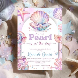 Puede incluir: Una tarjeta de invitación rectangular para baby shower con un diseño de acuarela en tonos pastel que muestra una gran concha abierta con perlas, una estrella de mar y coral. El texto dice: A LITTLE Pearl is on the way, Please join us to celebrate a baby shower honoring Hannah Brown, SATURDAY | MARCHA 25TH | AT 4:00 PM, HANNA'S HOUSE, ANY PLACE, ANY STREET 1223 NY, PLEASE RSVP +1 234 56789.