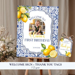 Puede incluir: Un cartel de bienvenida rectangular y una etiqueta de agradecimiento a juego con un patrón de azulejos azul y blanco, limones amarillos con hojas verdes y una foto central de un niño. El cartel dice Welcome to Olivia's First Birthday.