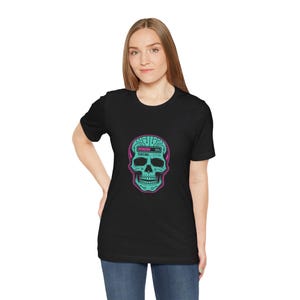 Könnte beinhalten: Ein schwarzes Kurzarm-T-Shirt mit einer Grafik eines türkisfarbenen Schädels, der auf der Schädeldecke mit Leiterplattenmustern versehen ist. Über dem Schädel befindet sich ein pinker Ladebalken bei 99 % mit dem Text CURSING... 1111% darunter.