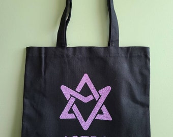 May include: Black canvas tote bag with a pink glitter star and the word "ASTRO" printed on the front.