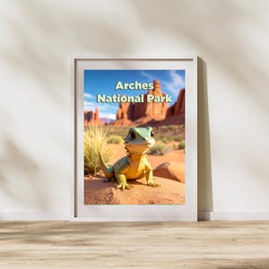 May include: A framed print featuring a cartoon lizard in a desert landscape. The lizard is green and yellow, with large eyes. The background shows red rock formations and the text "Arches National Park".