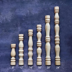 May include: Six unfinished wooden balusters of varying heights, ranging from 8 to 24 inches. Each baluster has a turned design with a series of rounded and cylindrical shapes. The background is a textured, dark blue surface.