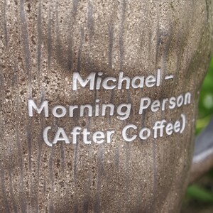 Puede incluir: Una taza texturizada con patr&oacute;n de veta de madera marr&oacute;n que presenta el texto grabado en blanco: Michael - Morning Person (After Coffee). La superficie tiene un aspecto rugoso y org&aacute;nico con estr&iacute;as verticales que imitan la corteza.