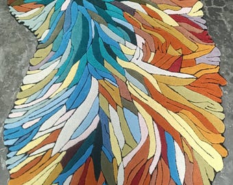 May include: An irregularly shaped area rug featuring a dense, tufted pattern of elongated, leaf-like segments in a vibrant palette of teal, blue, orange, yellow, red, olive green, and cream, creating a textured, multi-colored surface.