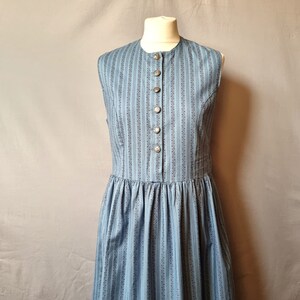 May include: A blue and white patterned sleeveless dress with a button-up front. The dress has a fitted bodice and a full skirt.