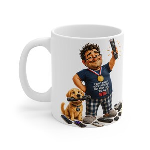 May include: A white ceramic mug featuring a cartoon illustration of a person wearing glasses, a medal, and a navy blue t-shirt with the text "I DON'T ALWAYS HOLD THE REMOTE BUT WHEN I DO... WE ALL WIN". A golden retriever puppy holds a remote in its mouth.