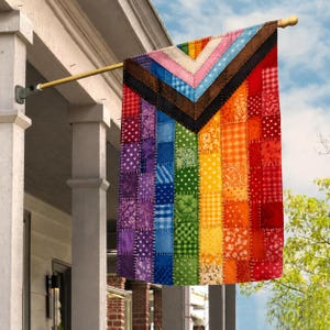 Puede incluir: Una bandera rectangular de tela con un diseño de patchwork de la bandera Progress Pride. La bandera está compuesta por varios cuadrados de tela estampados en tonos morado, azul, verde, amarillo, naranja, rojo, marrón, negro, blanco y rosa.