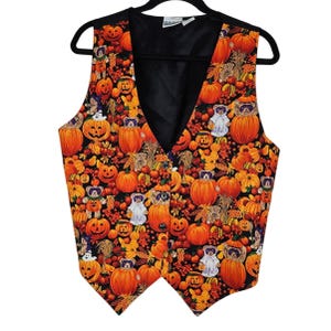 May include: A black sleeveless vest with a Halloween-themed print featuring pumpkins, bears, and ghosts. The print is in shades of orange, brown, and white on a black background.