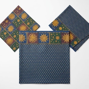 May include: Three square fabric napkins featuring celestial motifs. Two napkins display a grid of gold suns and stars on blue and green backgrounds. The third napkin features a border of gold suns above a field of small gold stars on a blue background.