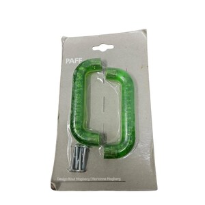 May include: Two green, rectangular door pulls with a bubbly texture are displayed on a cardboard backing. The brand name "PAFF" is printed at the top. The text "Design Knut Hogberg/Marianne Hogberg" is printed at the bottom. Screws are included.