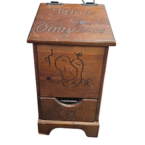 May include: A vintage wooden box with a hinged lid and a drawer. The box is stained a warm brown and features carved designs, including a fruit motif and the words "Talons & Omyuns" on the lid. A metal handle is attached.