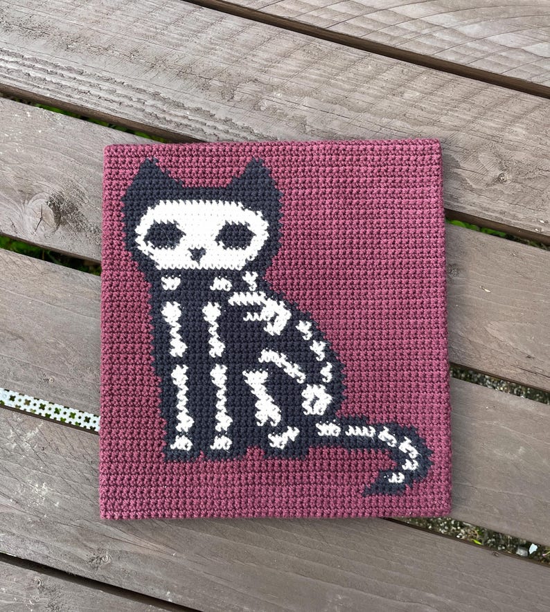 Peut inclure: Carr&eacute; crochet&eacute; avec un motif de chat squelette noir et blanc sur fond bordeaux. Le chat est assis, avec les d&eacute;tails de son squelette visibles. Cet article fait main est adapt&eacute; pour les d&eacute;corations d'Halloween.