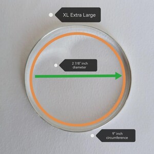 Peut inclure: Un objet circulaire transparent avec un contour orange et un diam&egrave;tre de 7,3 cm. La circonf&eacute;rence est de 22,9 cm. Le texte "XL Extra Large" est affich&eacute; au-dessus de l'objet.