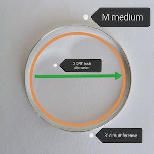 Peut inclure: Un objet circulaire transparent avec un anneau int&eacute;rieur orange et un bord ext&eacute;rieur argent&eacute;. Le diam&egrave;tre est de 6,67 cm et la circonf&eacute;rence de 20,32 cm. Le texte "M medium" est &eacute;galement pr&eacute;sent.