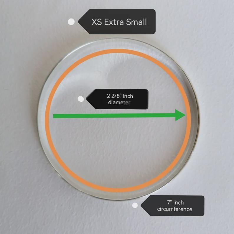 May include: A clear, circular bracelet with an orange inner ring. The diameter is 2 2/8 inches, and the circumference is 7 inches. The text indicates an XS Extra Small size.