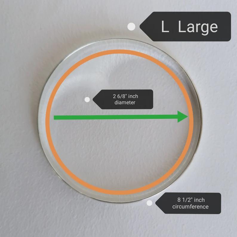 May include: A clear, circular object with an orange inner ring and a diameter of 2 6/8 inches. The circumference is 8 1/2 inches. The text "L Large" is displayed on a black label.