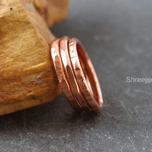 May include: A set of three copper rings with a hammered, textured finish. The rings are stacked together and feature a metallic, reddish-brown color. The text ShreejewelrsIN is visible on the right side of the image near the rings.
